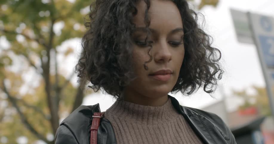 A woman is standing outside looking down