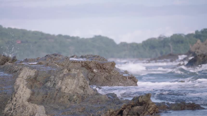 Serene slow-motion footage of ocean waves splashing against coastal rocks