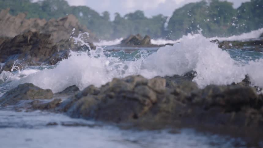 Dramatic slow-motion footage captures the power of ocean waves as they crash over jagged coastal rocks