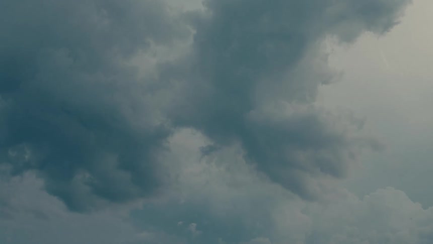 Flashes of lightning appear within dark, turbulent storm clouds