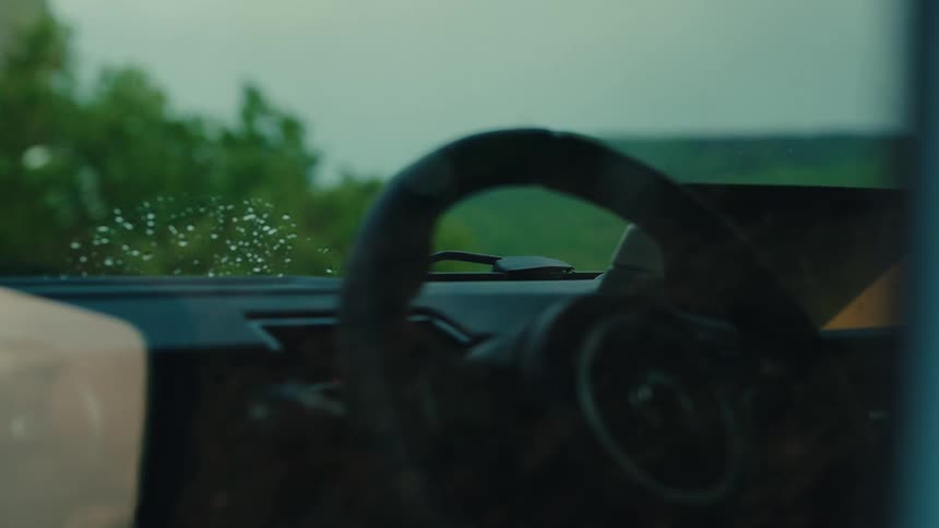 Slow motion shot of windshield wipers clearing raindrops off a car's windscreen on a gloomy, rainy day