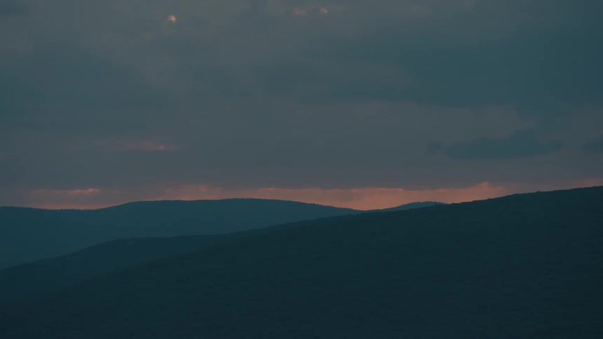 A moody twilight view of silhouetted mountain ranges with the last glow of sunset on the horizon