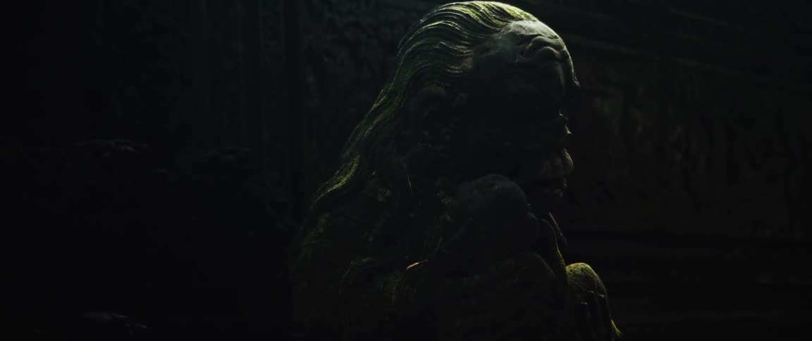 A mysterious ancient stone statue covered in moss sits in the darkness of a hidden temple