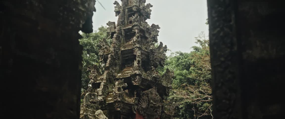 A slow pan reveals an ancient, moss-covered stone temple with intricate carvings in a dense jungle