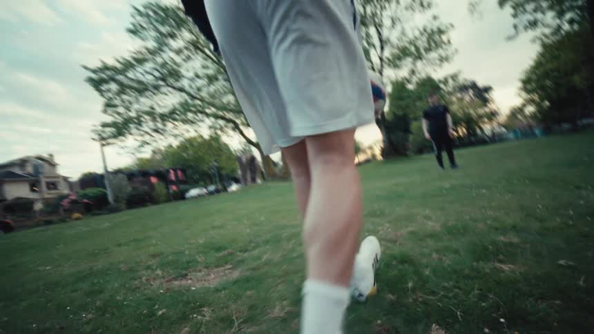 Dynamic low-angle slow-motion shot follows a soccer player's feet as they expertly dribble and kick a ball in a park