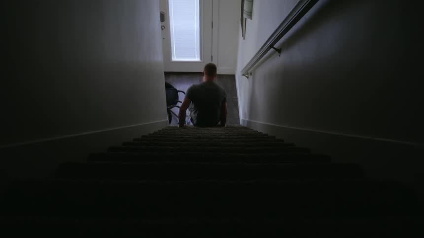 Man gets out of a wheelchair and climbs up the stairs backwards