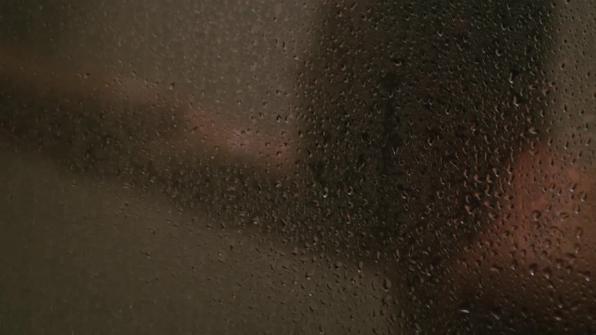 A man is taking a shower behind the glass