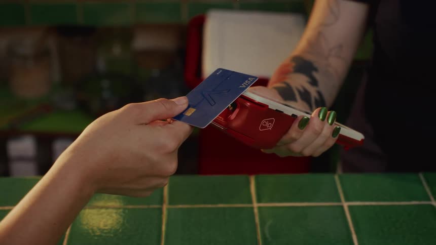 A close-up slow-motion shot of a customer inserting a credit card into a payment terminal to complete a purchase