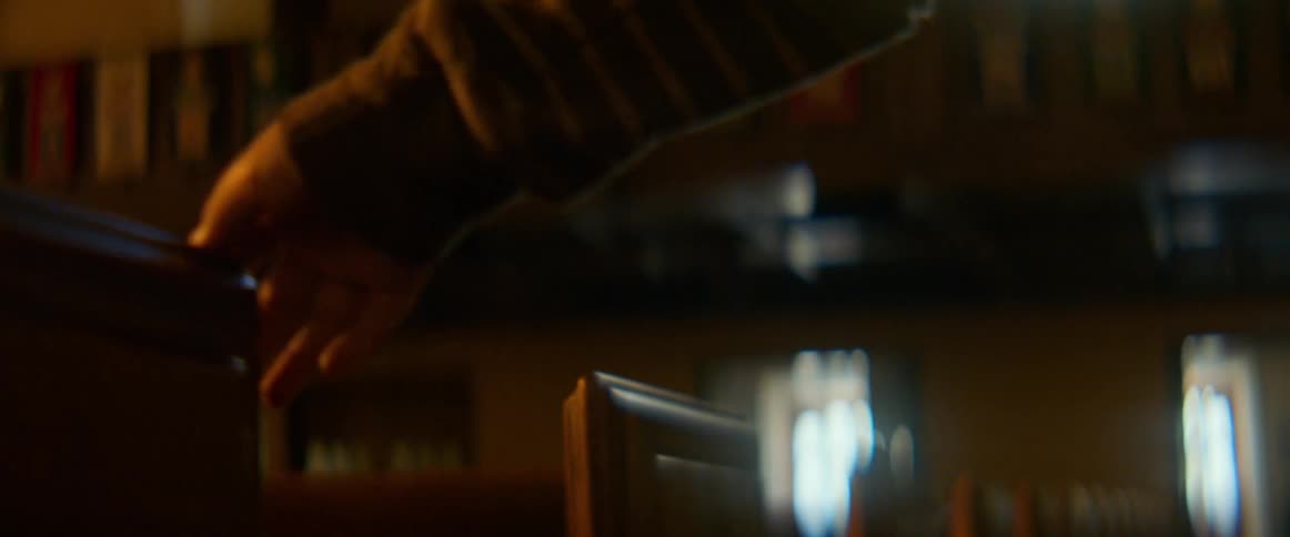 A close-up shot of a hand anxiously fidgeting on the back of a wooden church pew