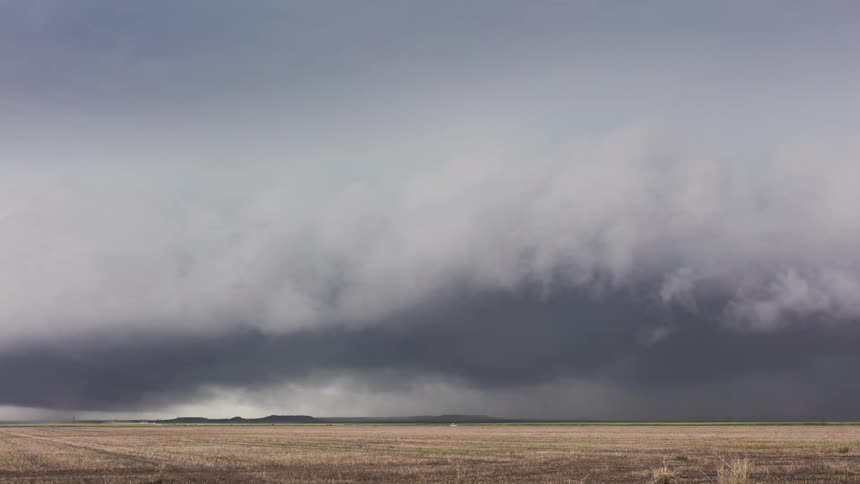 Storm clouds form and move across a road and field