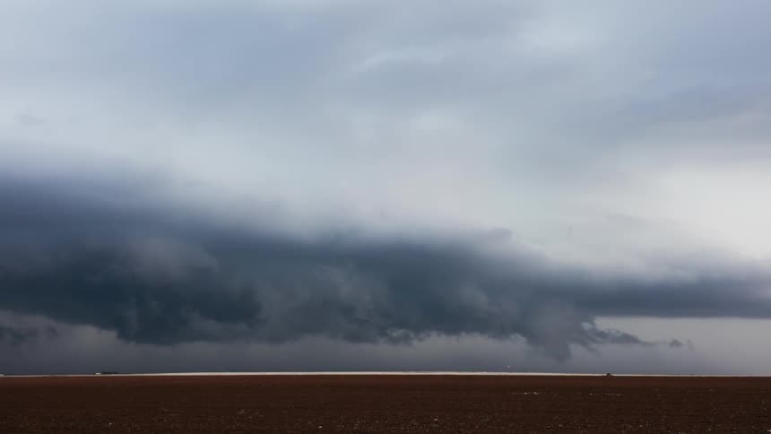 Storm clouds rotate and pass over an open field