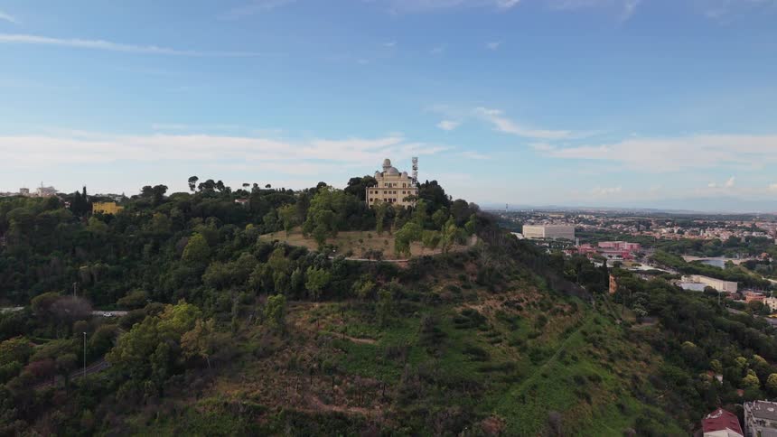 Slow aerial approach towards the historic Rome Astronomical Observatory on Monte Mario hill, with the city of Rome in the background