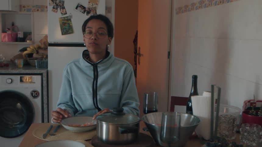 A young woman with glasses enjoys eating delicious shrimp in slow motion while sitting at her kitchen table