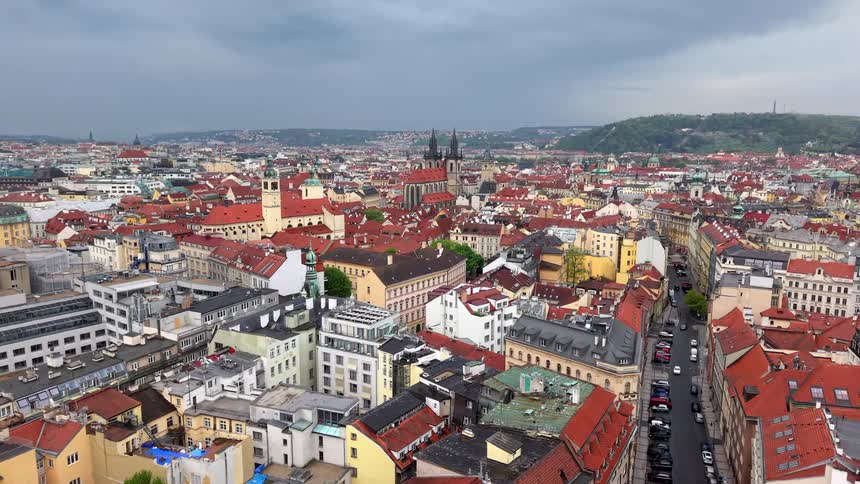 A slow aerial pullback reveals the historic red rooftops and cityscape of Prague, Czech Republic under a cloudy sky