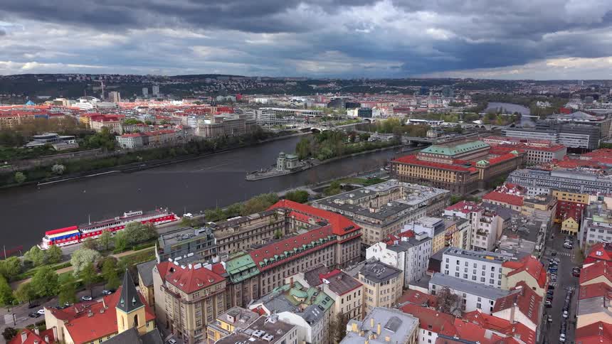 High-angle aerial pull-back shot reveals the historic cityscape of Prague and the Vltava River under a dramatic cloudy sky