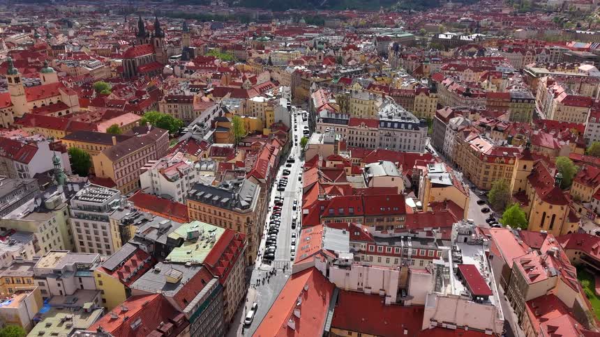 A slow aerial pullback reveals the historic cityscape of Prague, Czech Republic, with its iconic red rooftops and bustling streets