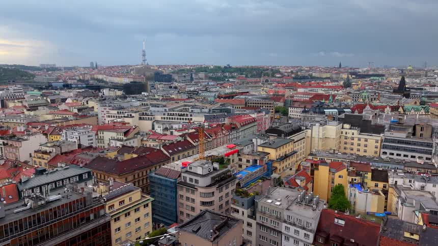 A slow zoom-out aerial view reveals the sprawling cityscape of Prague on a cloudy day