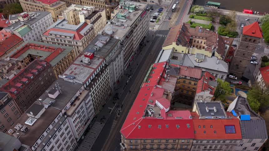A slow aerial view follows a tram through the historic streets of Prague, showcasing the city's classic architecture and red rooftops