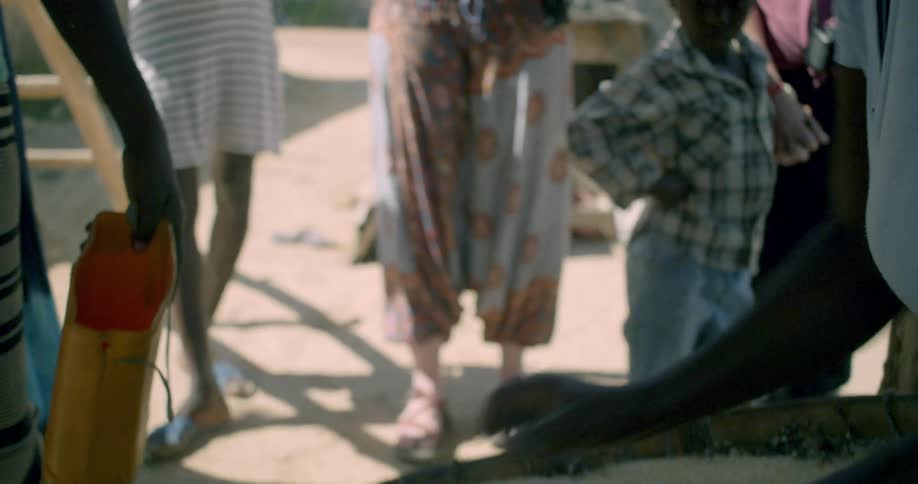 Slow motion close-up of African villagers sifting and preparing grain in a large basket outdoors