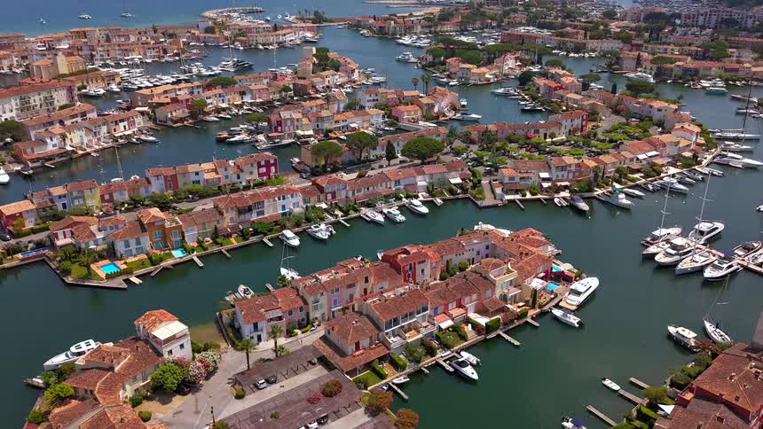 A stunning aerial view pans over the colorful seaside village of Port Grimaud on the French Riviera, revealing intricate canals and marinas filled with luxury yachts