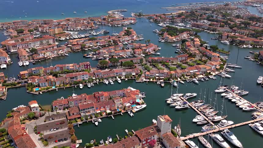 An aerial drone view reveals the stunning Venetian-style coastal town and bustling marina of Port Grimaud, France