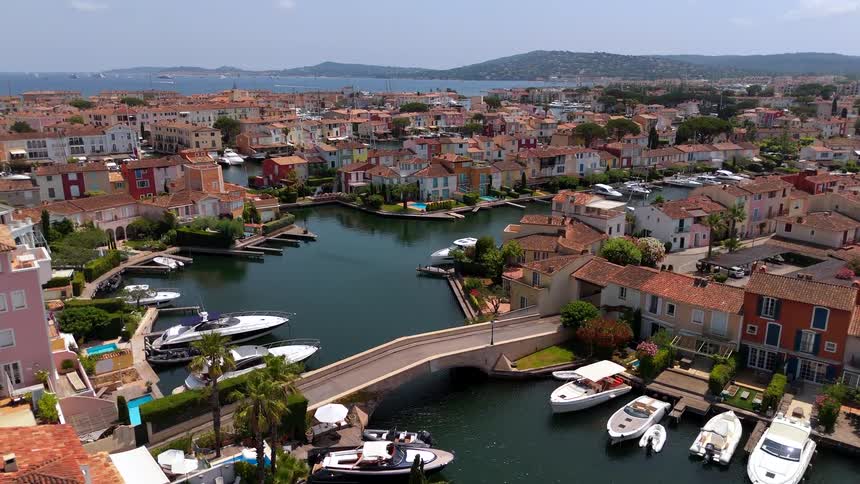 An aerial view ascends over the colorful coastal town of Port Grimaud, showcasing its beautiful canals, docked boats, and charming houses