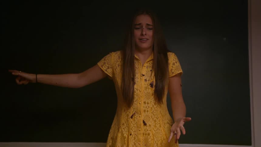 A young woman wearing a yellow dress cries in disgust after being hit with food