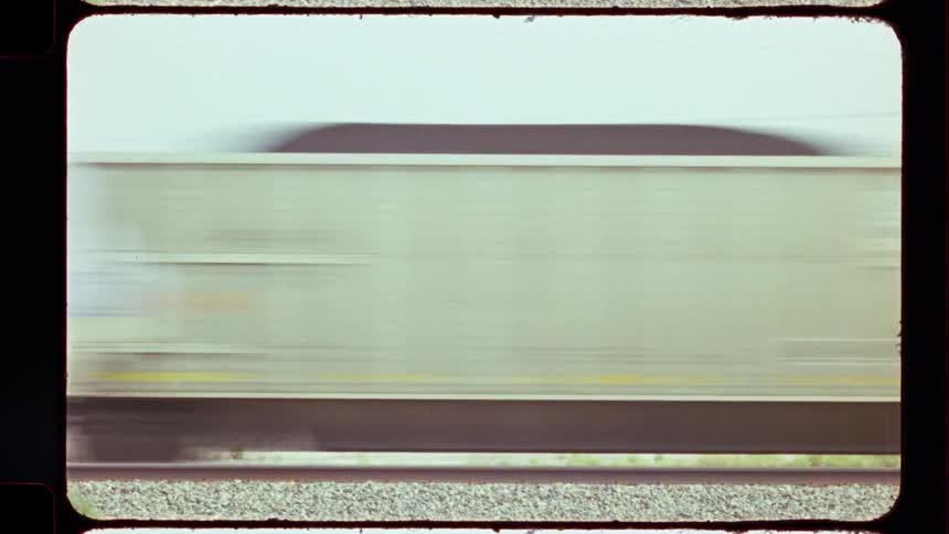 A close-up of a coal-filled train car speeding by in a motion blur, captured on vintage film