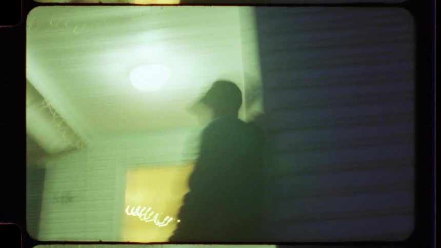 Grainy and blurry 8mm film footage captures a dreamlike memory of people on a porch at night