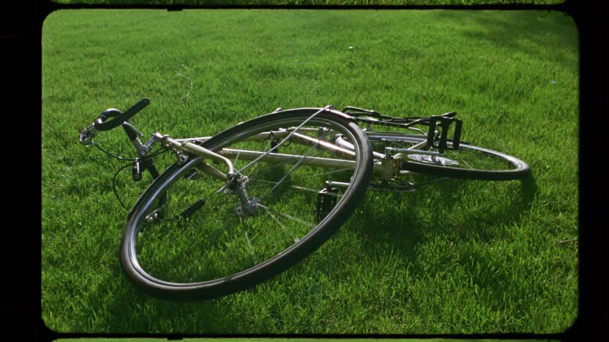 Retro 8mm film reveals a still shot of a bicycle resting on the grass on a sunny day
