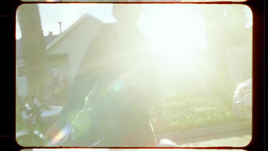 Vintage 8mm footage of a person juggling a soccer ball on a sunny suburban street