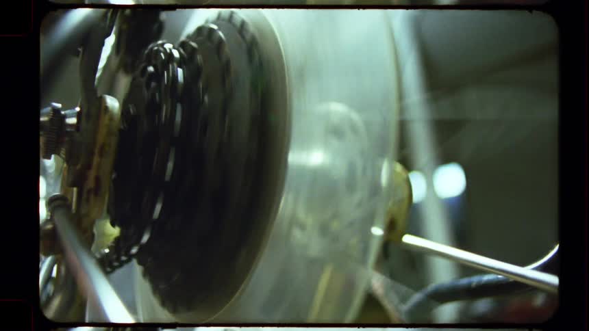 A close-up of a bicycle's rear gears and wheel spinning captured on vintage film