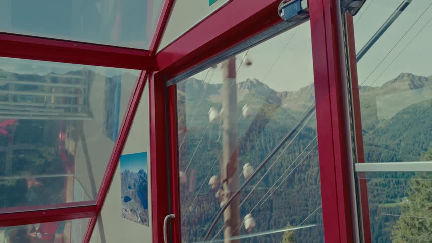 Ascending a mountain in a red gondola, offering a breathtaking view of the alpine forest and peaks