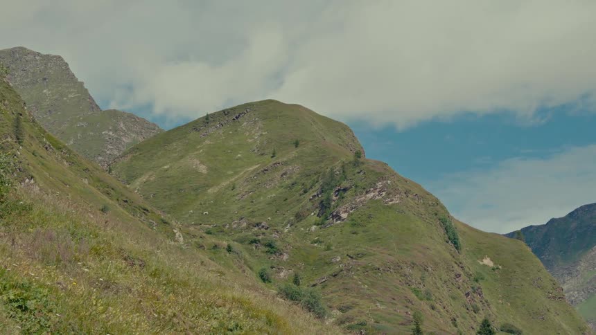 A serene view of lush green mountain peaks under a partly cloudy sky