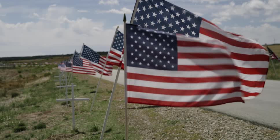 A row of flags fly in the wind