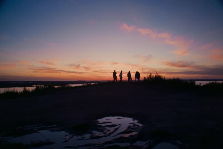 Silhouetted friends gather on a scenic overlook to watch a beautiful sunset together