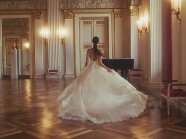 A graceful woman in a beautiful white ball gown walks into an opulent ballroom and begins to dance in slow motion