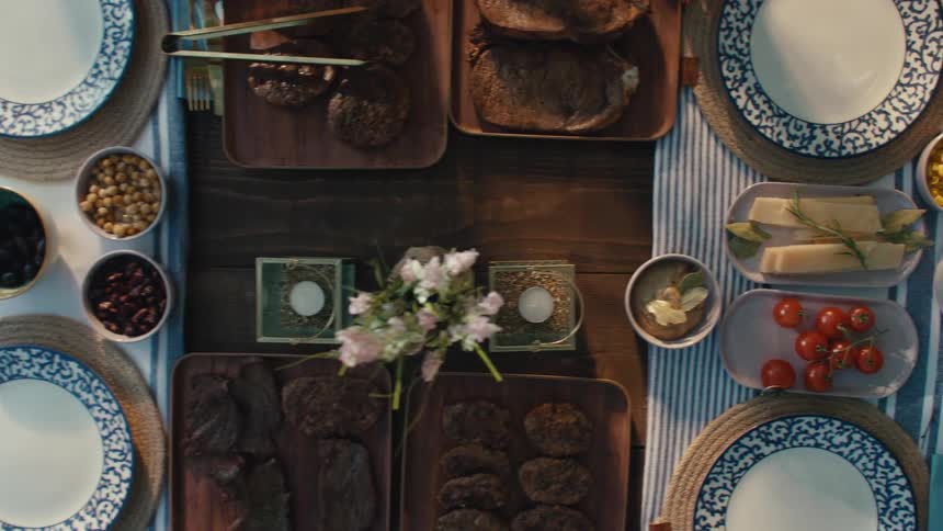 An overhead shot reveals a beautifully styled picnic table being filled with a colorful feast of Mediterranean-inspired dishes