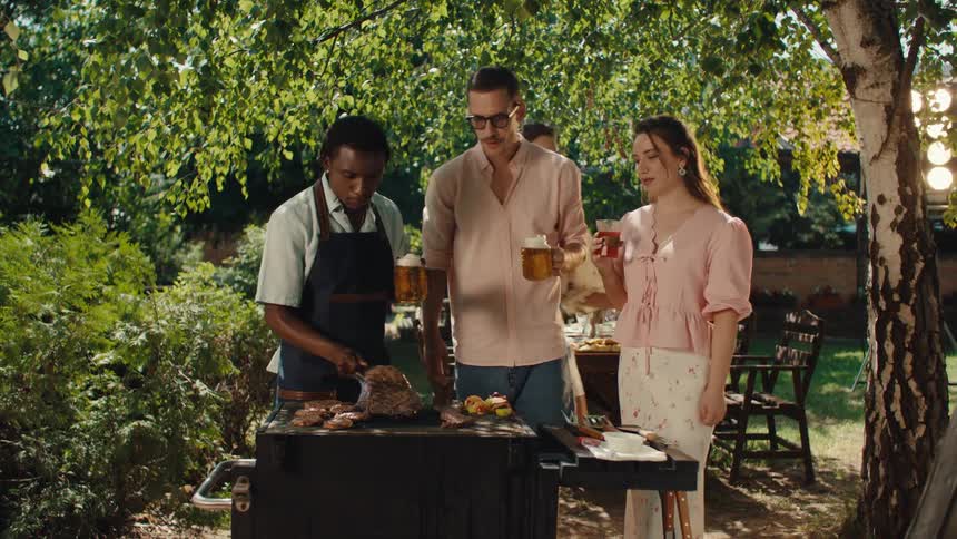 Happy diverse friends toast with drinks and enjoy a sunny backyard barbecue party together