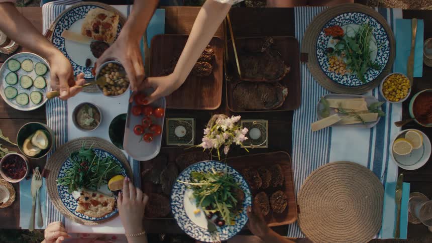 Top-down view of friends sharing a delicious outdoor barbecue feast, passing dishes and serving themselves