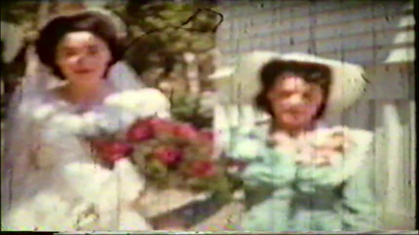 Vintage 8mm footage shows a smiling bride posing with her bridesmaids on a sunny wedding day