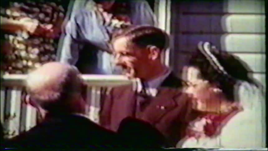 Vintage home movie captures a joyous bride and groom laughing and talking with guests at their wedding in the 1950s