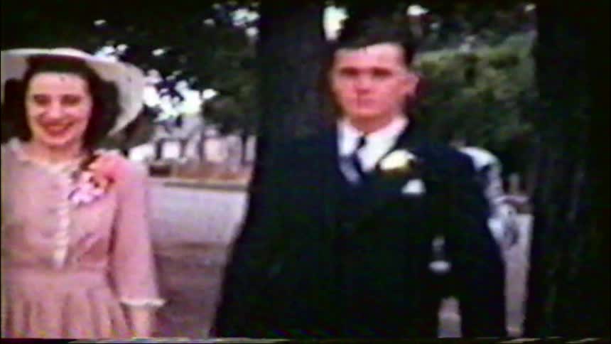 A happy bride and groom celebrate with their wedding party outdoors in this grainy vintage home movie from the 1940s
