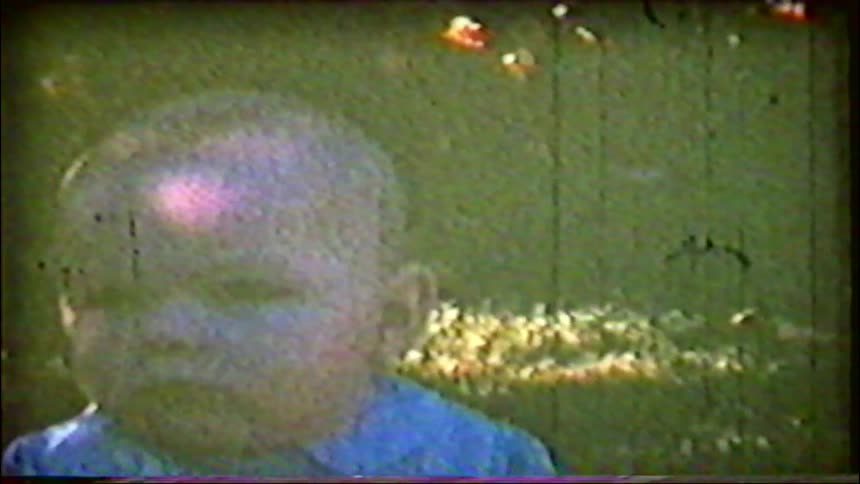 A grainy close-up of a sweet baby's face on a sunny day from vintage 8mm home movie footage