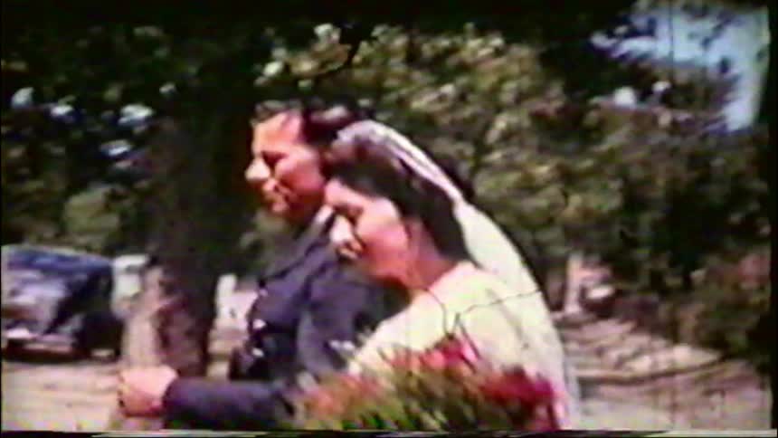 A bride and her military groom walk down a tree-lined street after their wedding in this authentic 1940s home movie footage