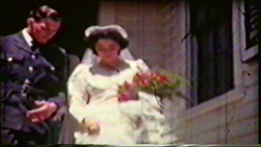 Vintage footage from the 1940s shows a newly married couple, with the groom in a military uniform, walking down the steps after their wedding