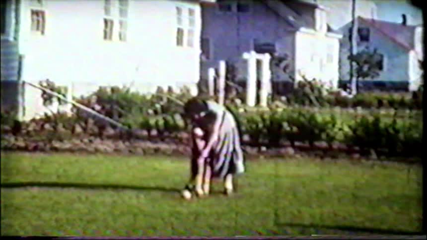 Archival footage from the 1950s shows a woman in a dress playing a game of croquet in a grassy suburban backyard