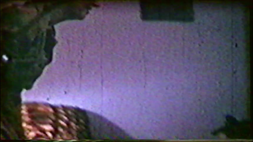 Vintage home movie captures a mother and child decorating a small Christmas tree together