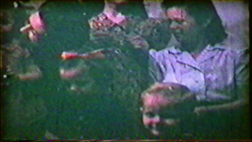 A nostalgic vintage home movie captures a happy family with their children posing in front of a Christmas tree