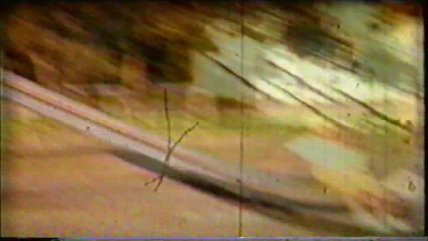Vintage 8mm film captures children having fun and taking turns going down a tall slide at a sunny playground
